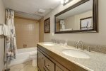 Full size bathroom with bathtub, shower, and dual vanities